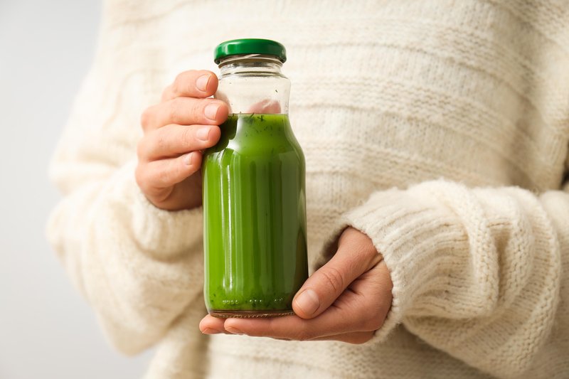zielony sok w dłoniach w butelce